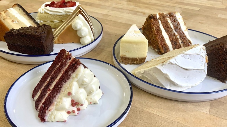 9 slices of cake on three white plates with wood background