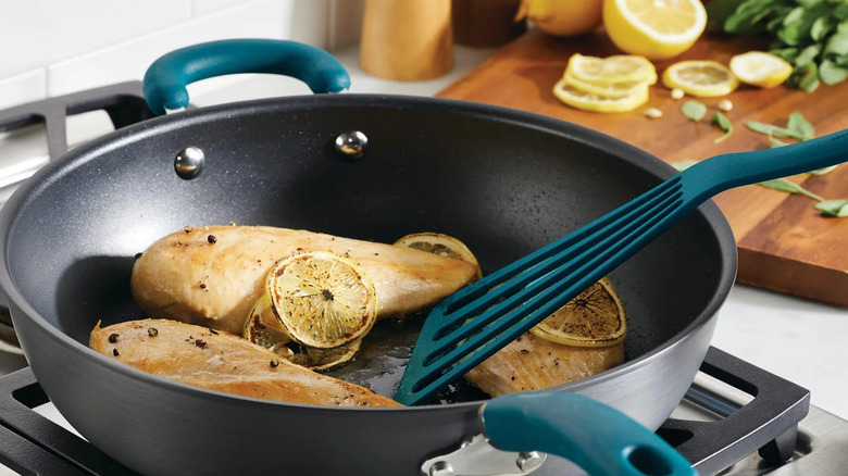 12.5-inch anodized nonstick induction deep frying pan with helper handle on a stove top with chicken cooking in it