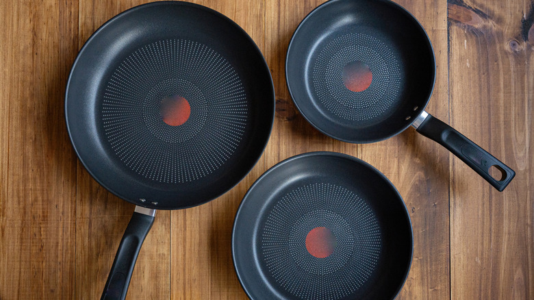 three different sized non-stick pans on a wooden surface