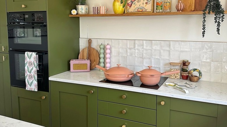 Our Place always pan on an induction stovetop in an aesthetic green-hued kitchen on a marble countertop
