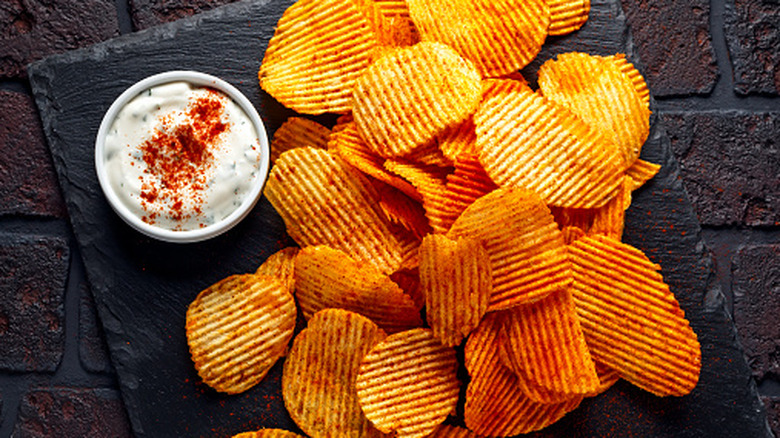 Spicy ridged potato chips with a bowl of dip