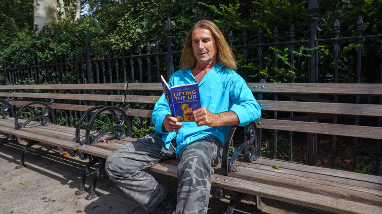 Fabio reads a book on a park bench in New York.