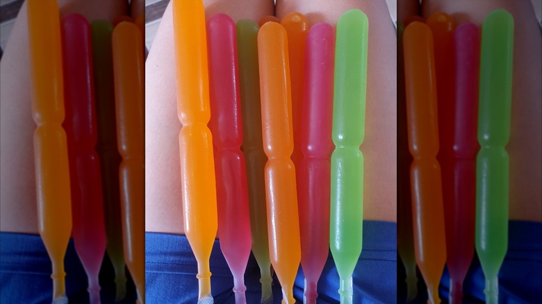Multicolored Mexican Bolis freezer pops resting on someone's legs