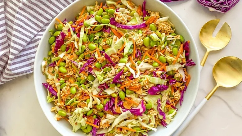 Crunchy ramen noodle salad in a bowl with utensils and napkin
