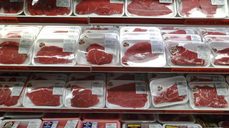 Several shelves of packaged raw beef in the refrigerated meat section of a supermarket
