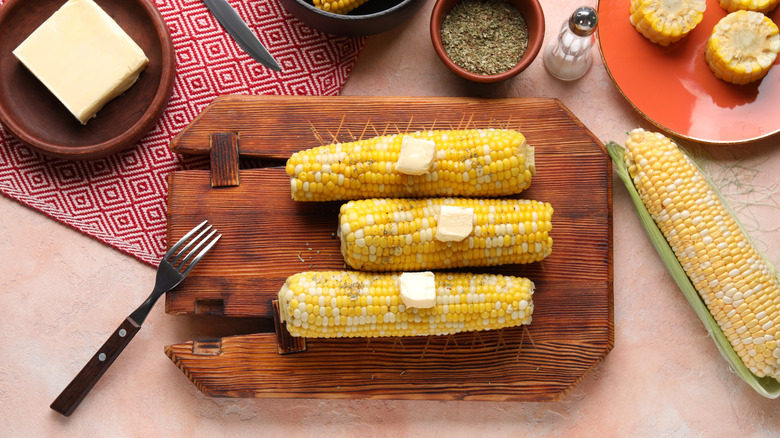 Corn cobs and butter on a chopping board