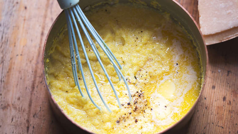 Overhead view of pot of polenta and a whisk