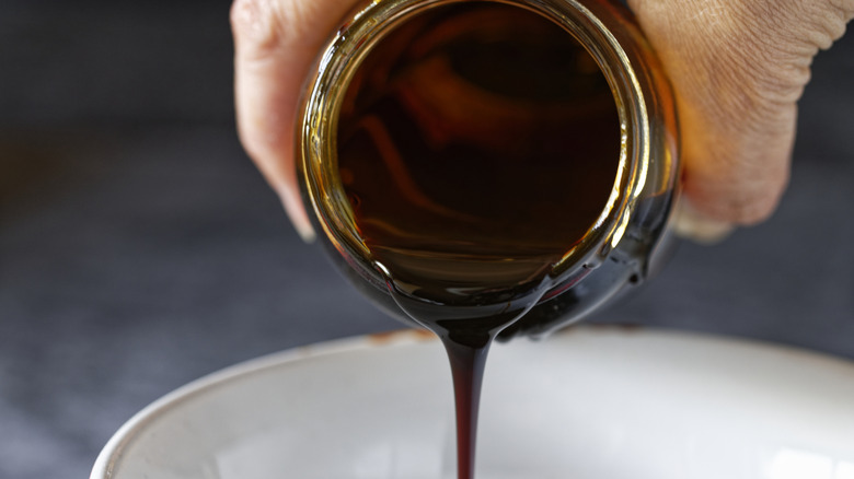 Person pouring molasses from a jar