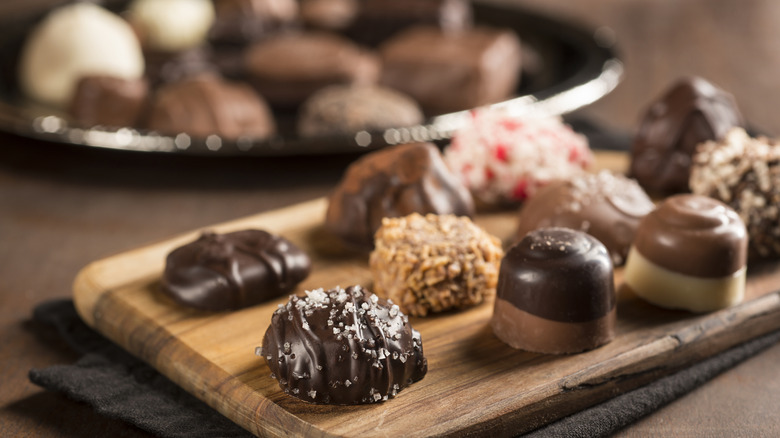 A close-up image of specialty chocolates arranged on a wooden cutting board