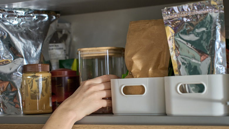 Hand grabbing pantry goods stored on a shelf