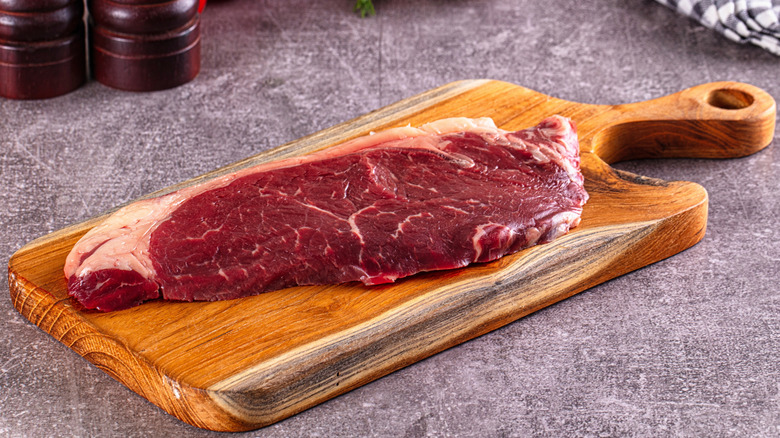 A raw piece of steak with a thick fat cap and thick streaks of marbling