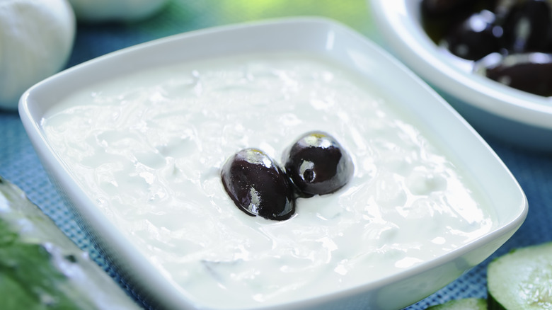 tzatziki sauce in a white platter with olives