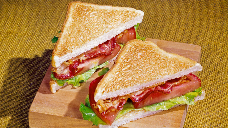 A BLT, cut in half on a block of wood