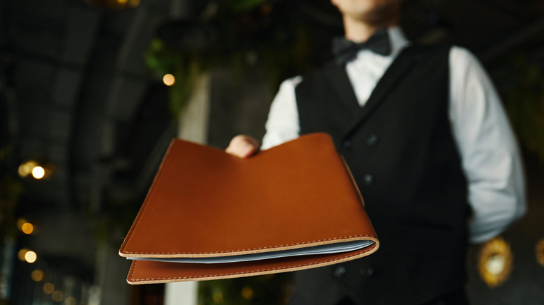 Server handing out brown leather menu