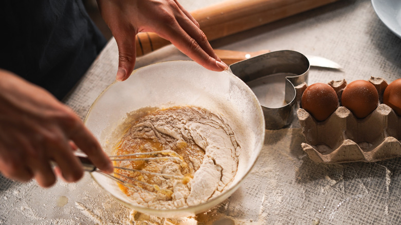 Woman mixing cake batter in bowl with eggs