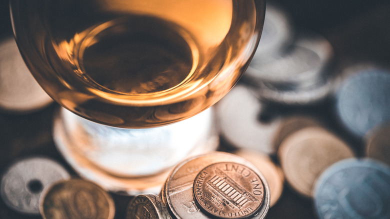 a glass of Scotch whisky surrounded by coins