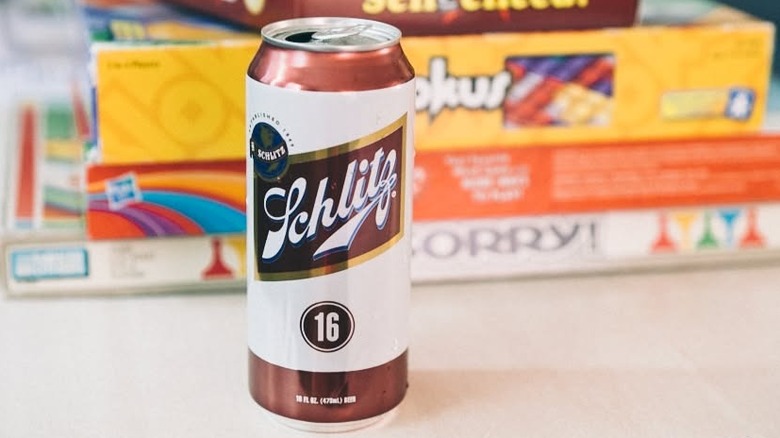 a 16-ounce can of Schlitz in front of a stack of board games