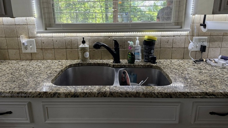 kitchen sink with granite countertops and beige backsplash below window