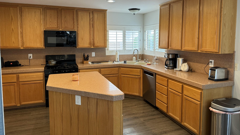 empty kitchen with maple cabinets white walls and and kitchen island