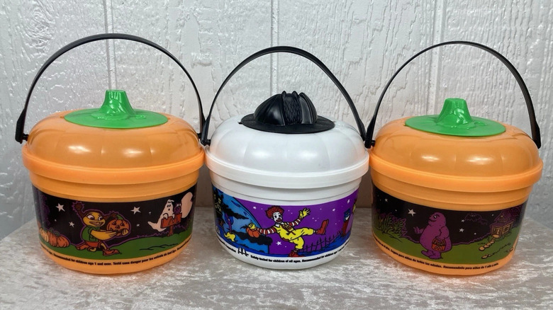 Three McDonald's Boo Buckets in orange and white colors on gray surface