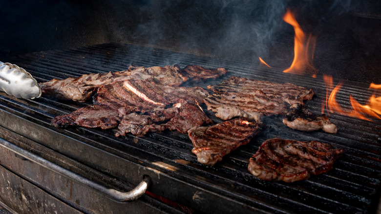 Char-grilled carne asada on flaming grill