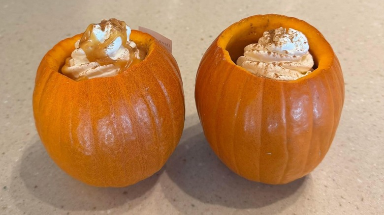Two small pumpkins filled with Starbucks Pumpkin Spice Lattes