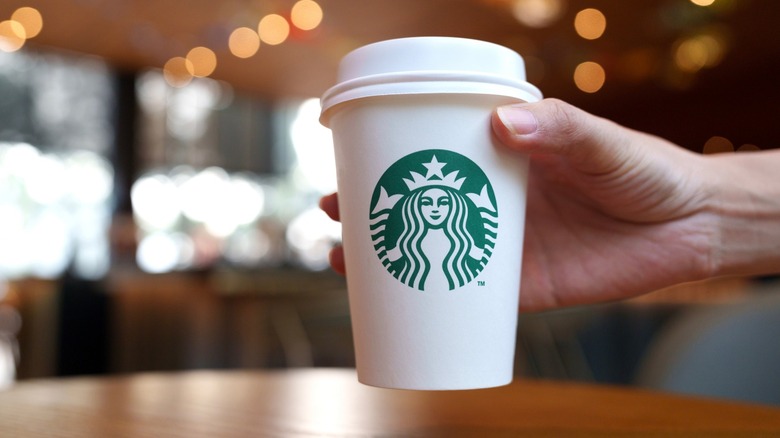 A hand holding a paper Starbucks cup