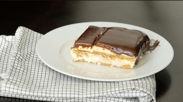 slice of Boston cream icebox cake on white plate placed on top of checkered kitchen towel