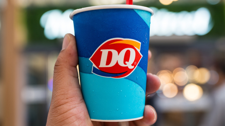 Hand holding blue paper Blizzard cup with Dairy Queen logo