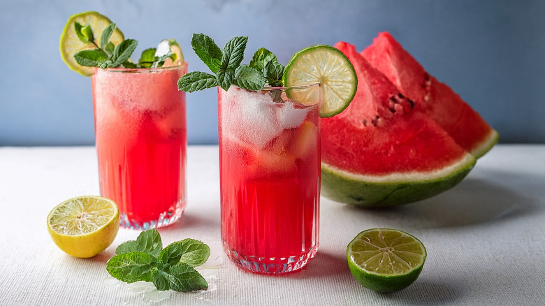 Watermelon juice and ice in glasses garnished with mint springs and limes.
