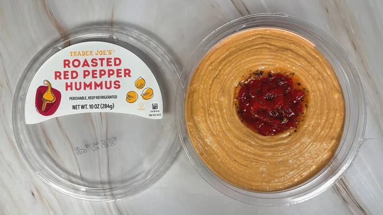 a container of Trader Joe's roasted red pepper hummus with the lid removed and placed beside it