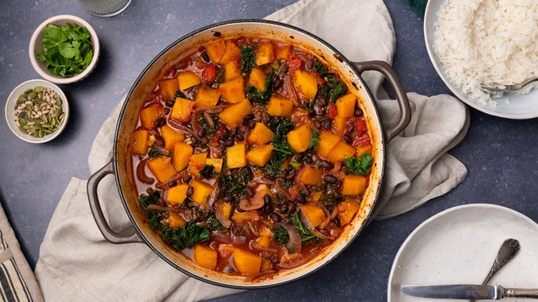 Pumpkin and black bean casserole in a Dutch oven with cilantro and pepita