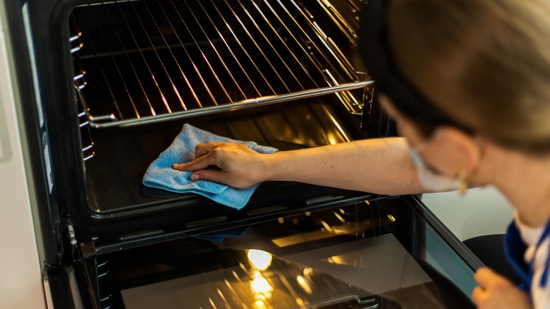 person cleaning oven