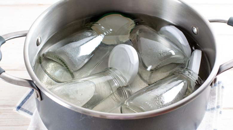 Sterilizing bottles and lids by boiling them in a pot of water