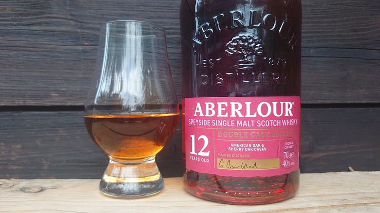 A close up of a tasting glass filled with Aberlour 12 with its bottle next to it