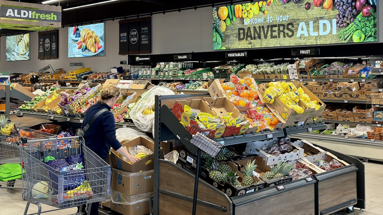 The interior of Danvers Aldi store with woman choosing fresh fruits