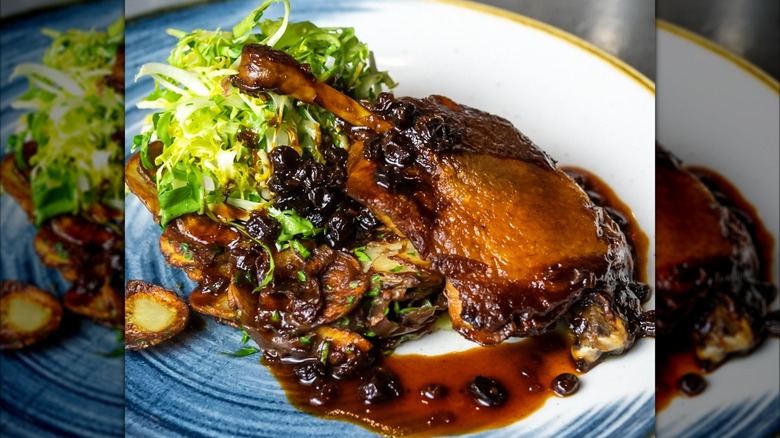 Duck confit with sauce, potatoes, and greens