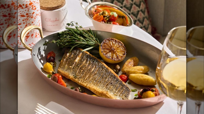 Fish and grilled citrus on serving tray on table with white wine