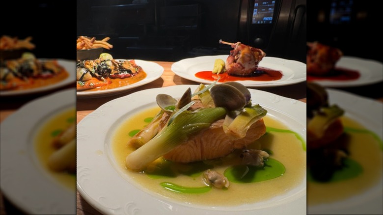 Confit trout with leeks on plate and other dishes in background