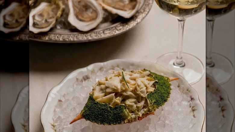 Deviled blue crab on ice with wine and tray of oysters in background