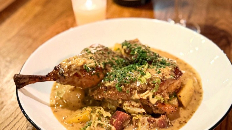 Braised chicken dish with sauce and candle in background