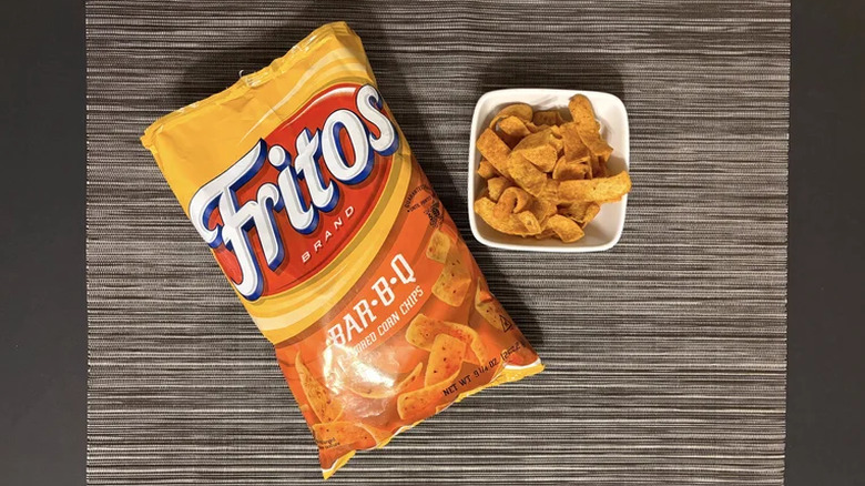 A bag of Fritos Bar-B-Q chips next to a bowl of corn chips.