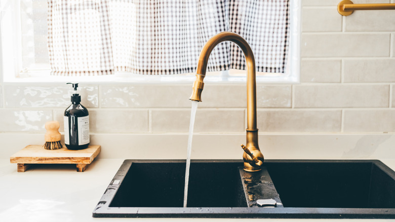 A sink with a gold kitchen faucet