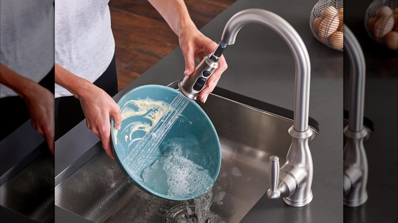 A person rinsing a bowl with a Moen Brantford Motionsense Wave faucet