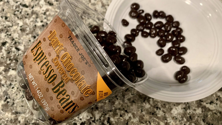 Container of Trader Joe's chocolate espresso beans pouring onto white plate
