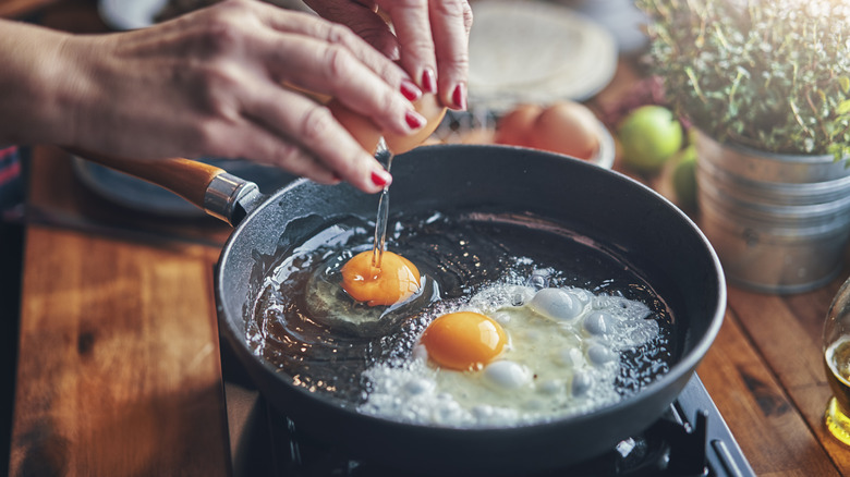 Cracking eggs into a frying pan