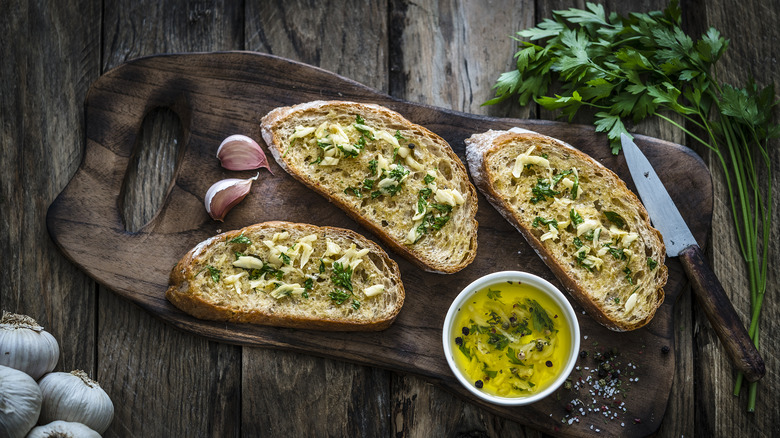 Garlic bread slices and cilantro on a wooden board