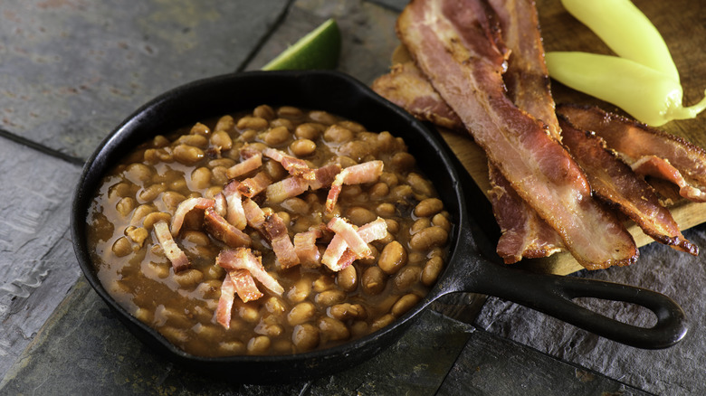 Baked beans topped with bacon in cast iron skillet