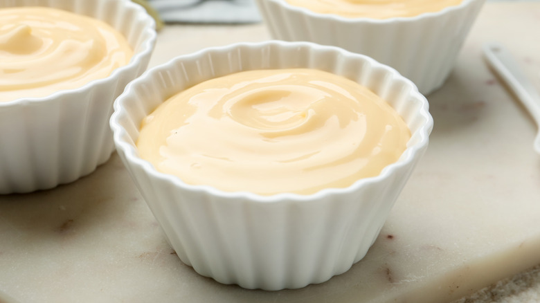 White ceramic dishes of vanilla pudding.