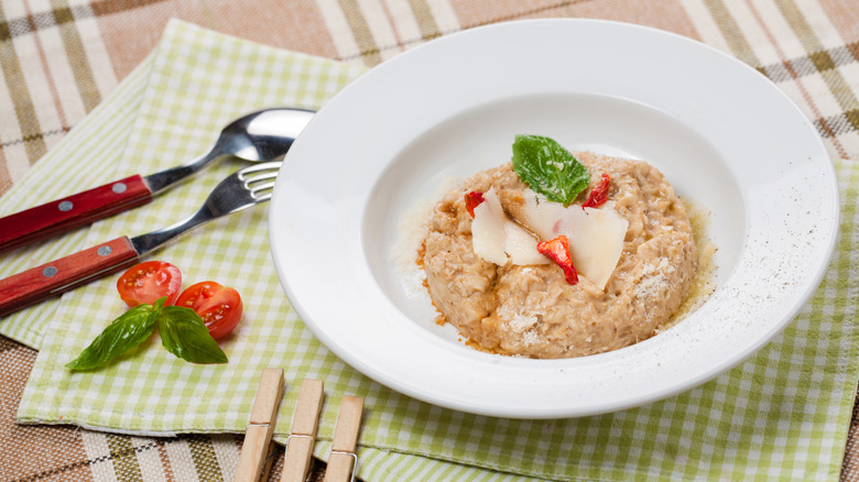 A bowl of savory oatmeal finished with parmesan basil and tomato
